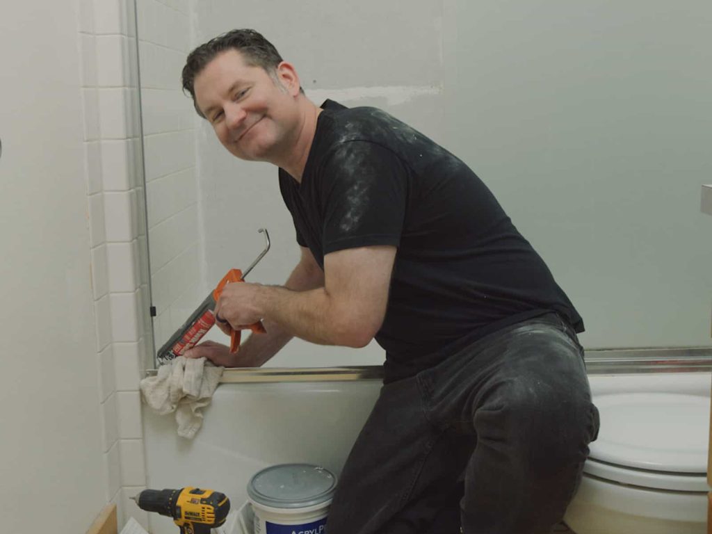 Technician caulking the edge of a bathtub